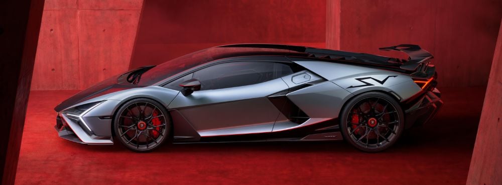 Lamborghini Revuelto grise présentée dans un décor rouge