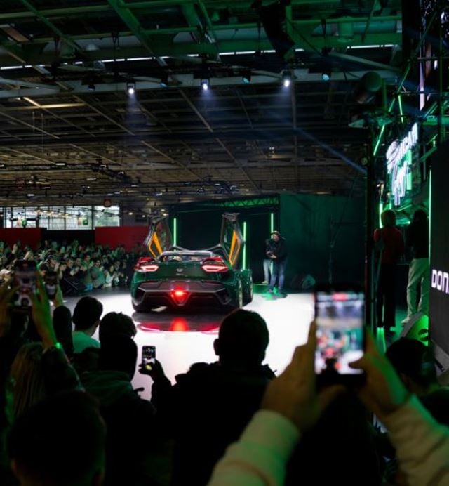 Donkervoort sports car demonstration on stage in front of automotive show visitors.