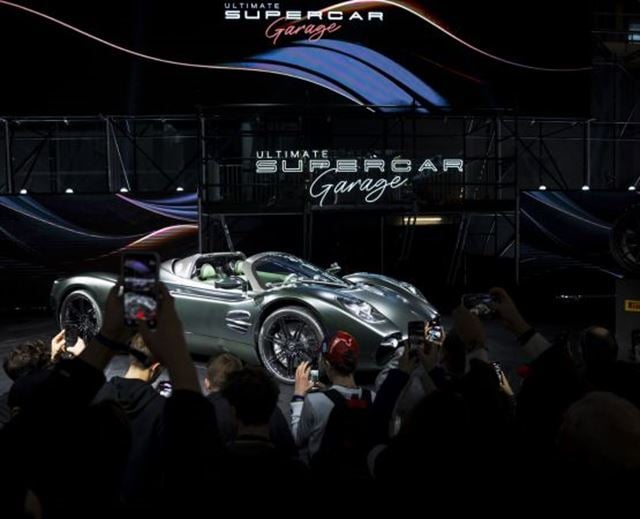 Présentation d’une supercar grise sur la scène de l’Ultimate Supercar Garage devant un public de passionnés.