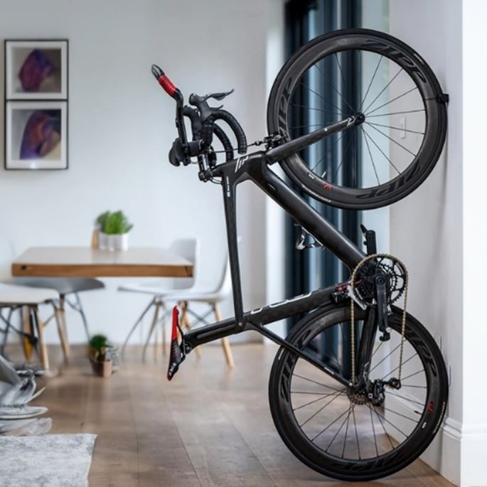Homme élégant arrivant à vélo devant un bâtiment moderne, en noir et blanc, ambiance urbaine et raffinée.