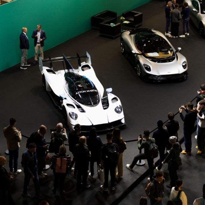 Nighttime view of a luxury car approaching the entrance of a modern exhibition center.