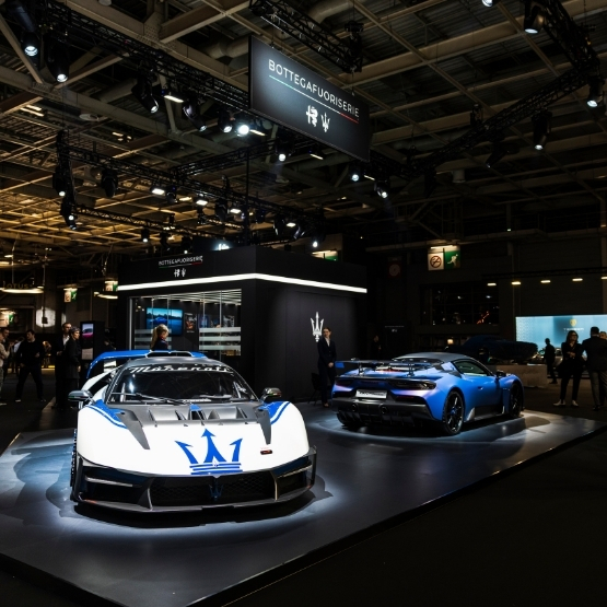Photo d’une supercar mise en scène dans un espace d’exposition luxueux, avec éclairage dramatique, structure architecturale et ambiance élégante, suggérant une prise de parole sur scène.
