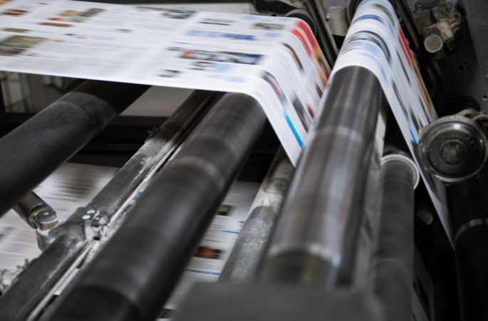 Machine d’impression industrielle en train d’imprimer des feuilles de papier en couleur.