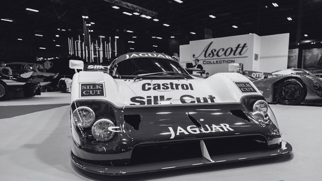 Photo noir et blanc d'une supercar Jaguar sur un stand de grand machant lors d'un salon automobile