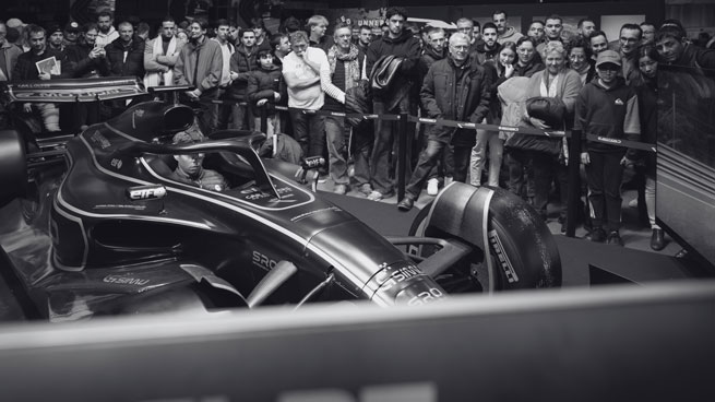 Photo noir et blanc d'un simulateur de supercar présent sur le stand d'un club lors d'un salon de l'automobile