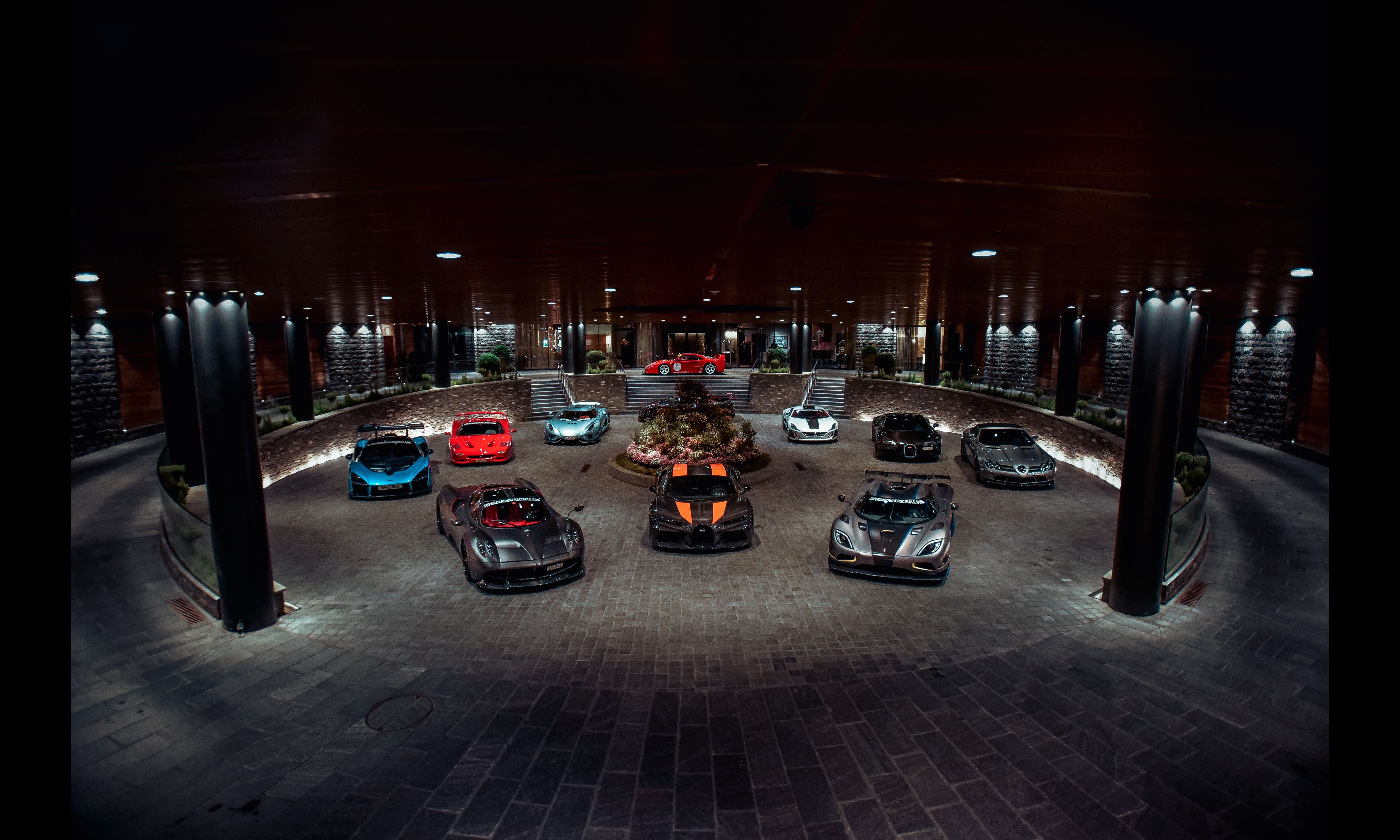 large circular room filled with supercars under spotlights